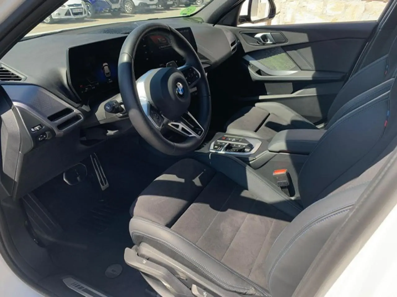 Intérieur avant droit de BMW Série 1 118D blanc, sellerie Alcantara noire et volant M cuir multifonctions.