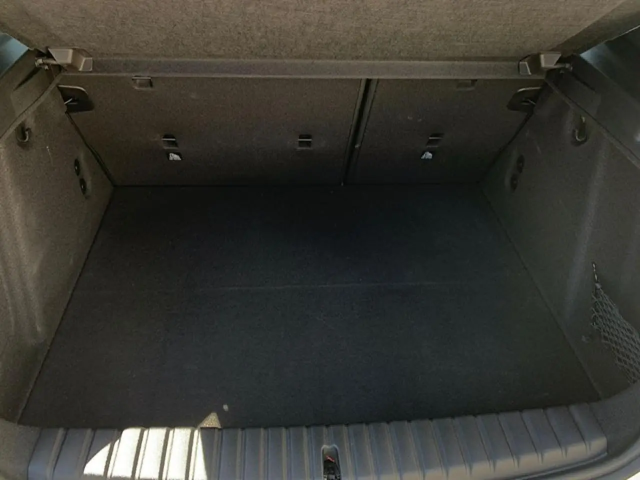 Coffre spacieux de BMW Série 1 118D M Sport 2025, vue intérieure avec filet côté droit et crochets porte-sacs.