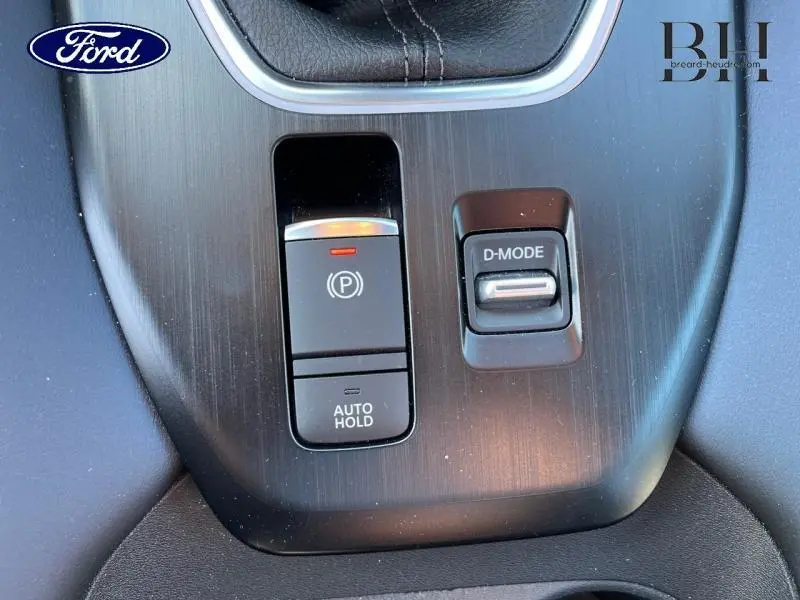 Gros plan sur la console centrale du Nissan Qashqai 1.3 Mild Hybrid gris argile, avec frein à main électronique et bouton D-MODE.