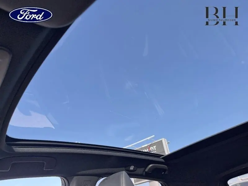 Toit panoramique ouvert vu de l'intérieur d'un Nissan Qashqai Gris Argile, ciel bleu visible au-dessus