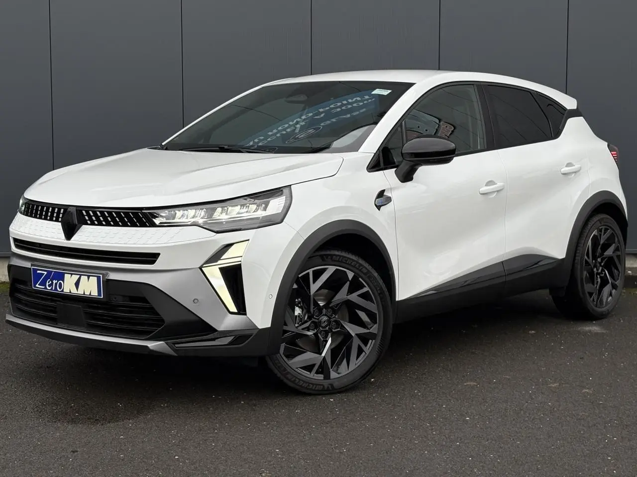 Renault Captur blanc nacré en 3/4 avant droit, avec jantes noires et détails noirs contrastants.