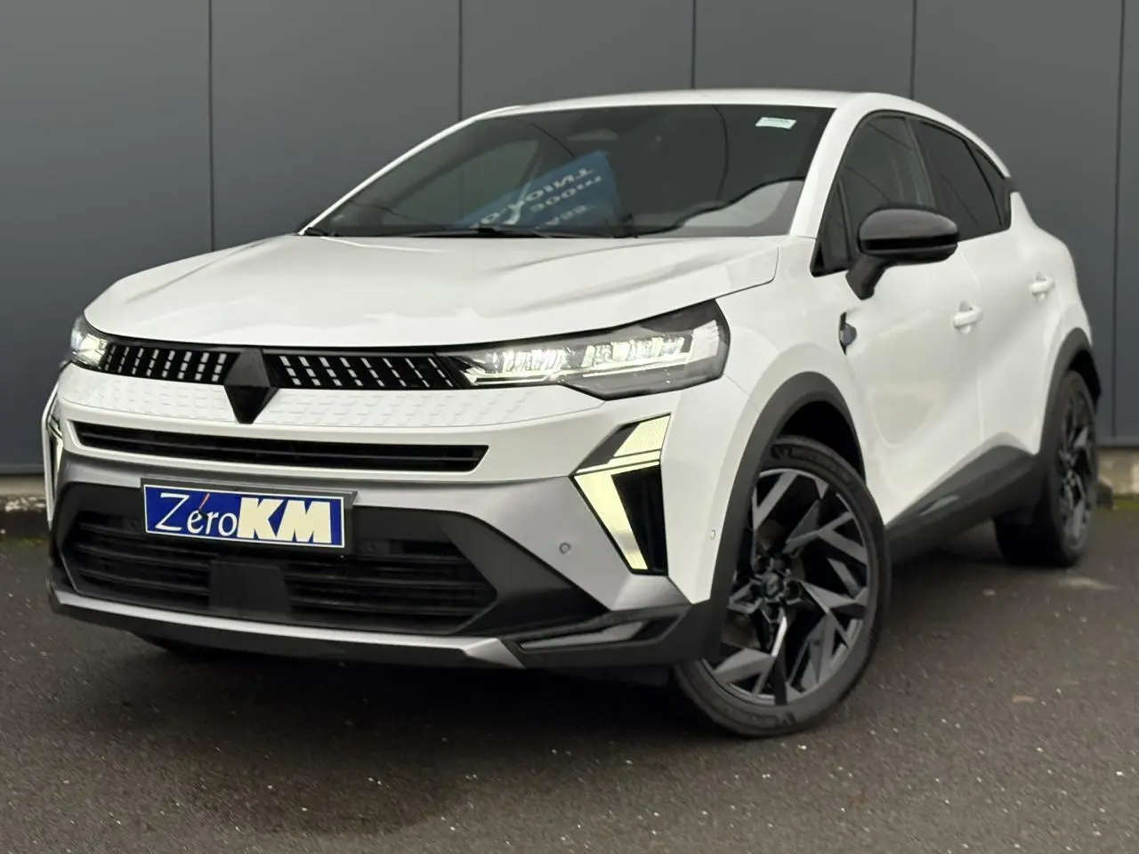 Renault Captur blanc nacré en 3/4 avant droit, avec feux LED et jantes aluminium noires distinctives.