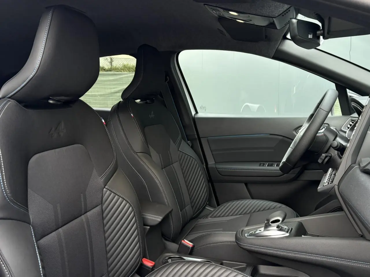 Vue intérieure côté droit du Renault Captur Esprit Alpine 2025, sièges noirs avec logo Alpine embossé.