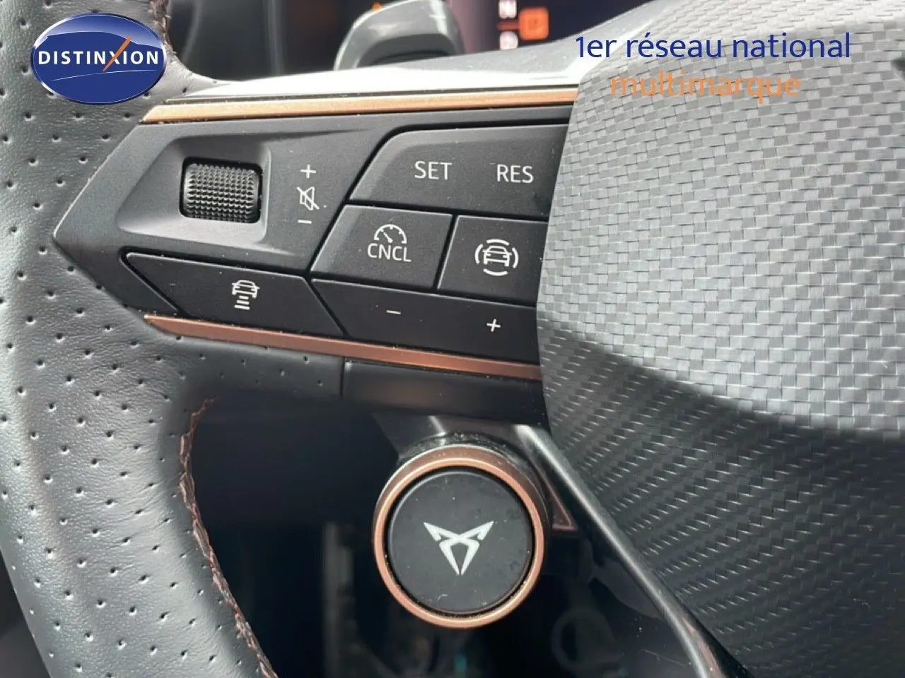 Gros plan sur le volant de la CUPRA Formentor 2025, montrant les commandes et le logo sur fond noir texturé.