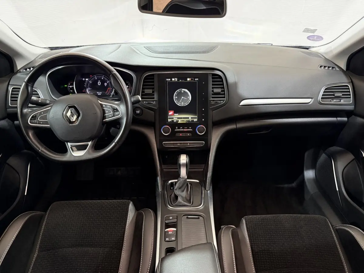 Vue intérieure avant de la Renault Mégane Intens 2019, tableau de bord noir avec écran tactile vertical et volant cuir multifonctions.
