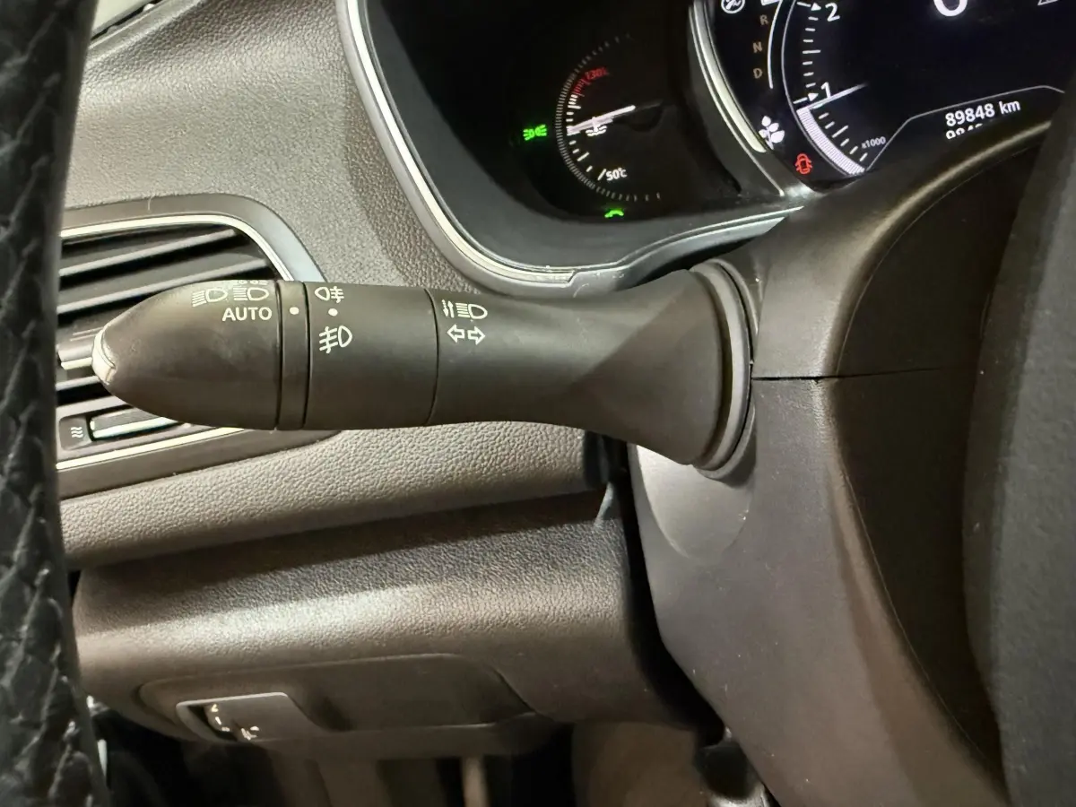 Gros plan sur la commande des phares et clignotants à gauche du volant dans l’habitacle noir de la Renault Mégane 2019.