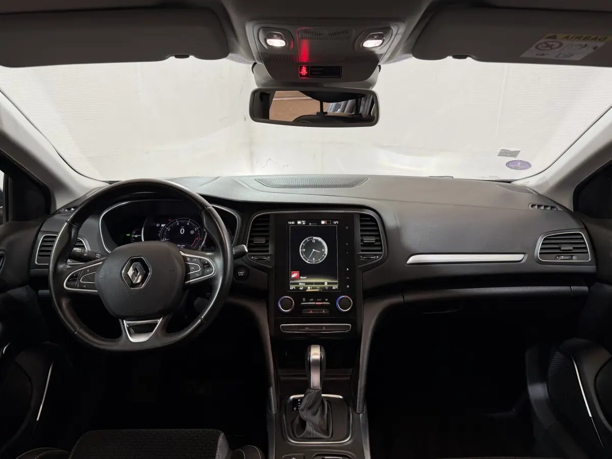 Vue intérieure frontale du tableau de bord de la Renault Mégane Intens 2019 avec écran tactile vertical et volant cuir noir.