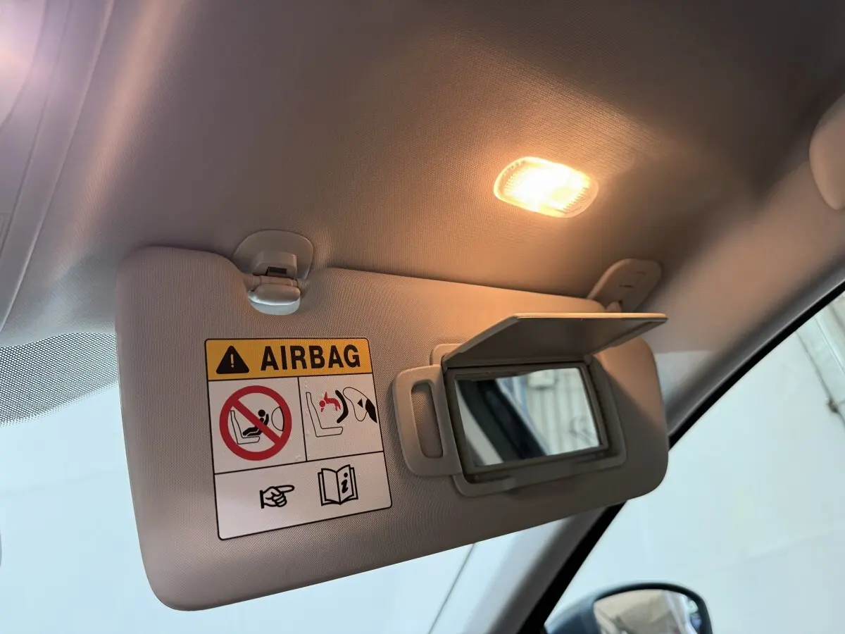 Détail du pare-soleil côté conducteur avec miroir ouvert et lumière intérieure allumée dans une Renault Mégane gris foncé.