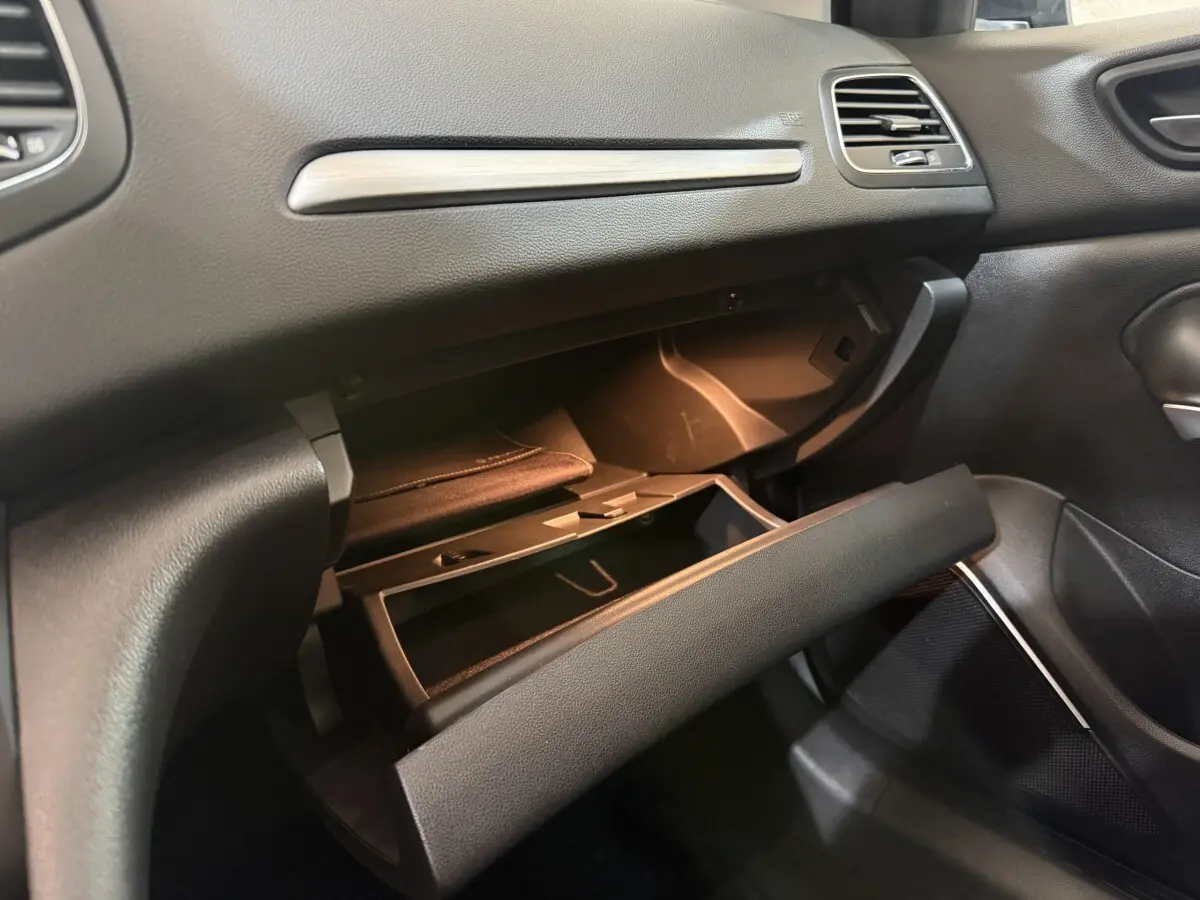 Intérieur de la Renault Mégane Intens 2019, vue côté passager sur la boîte à gants ouverte avec éclairage intérieur.