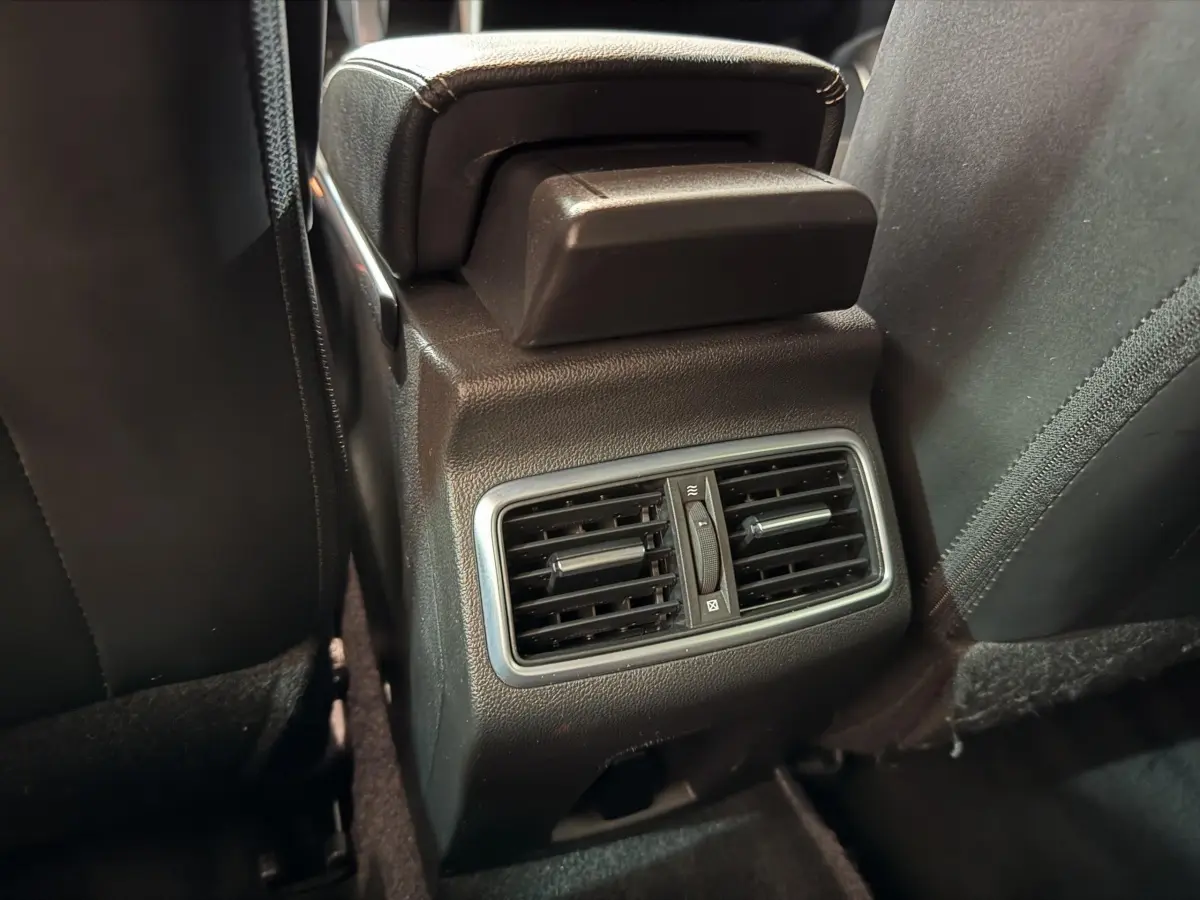 Détail des aérateurs arrière noirs avec réglage central, entre les sièges avant d'une Renault Mégane Intens gris foncé.