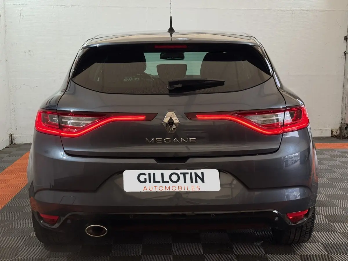 Vue arrière d'une Renault Mégane gris foncé avec feux LED allumés dans un garage.