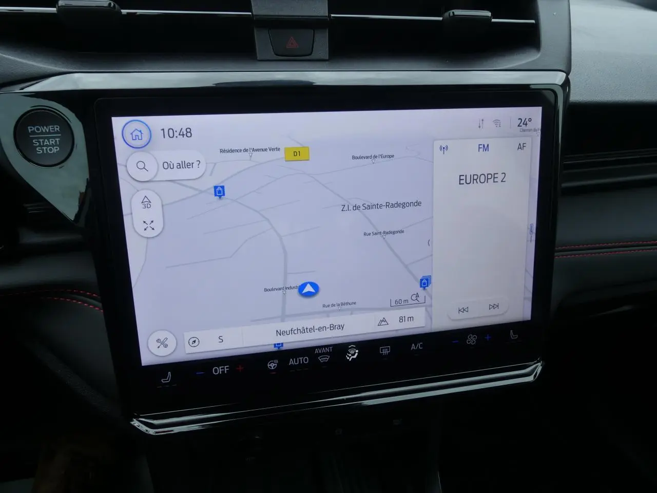 Écran tactile 12 pouces du Ford Puma 2025 affichant la navigation et la radio, avec finition intérieure noire et surpiqûres rouges.