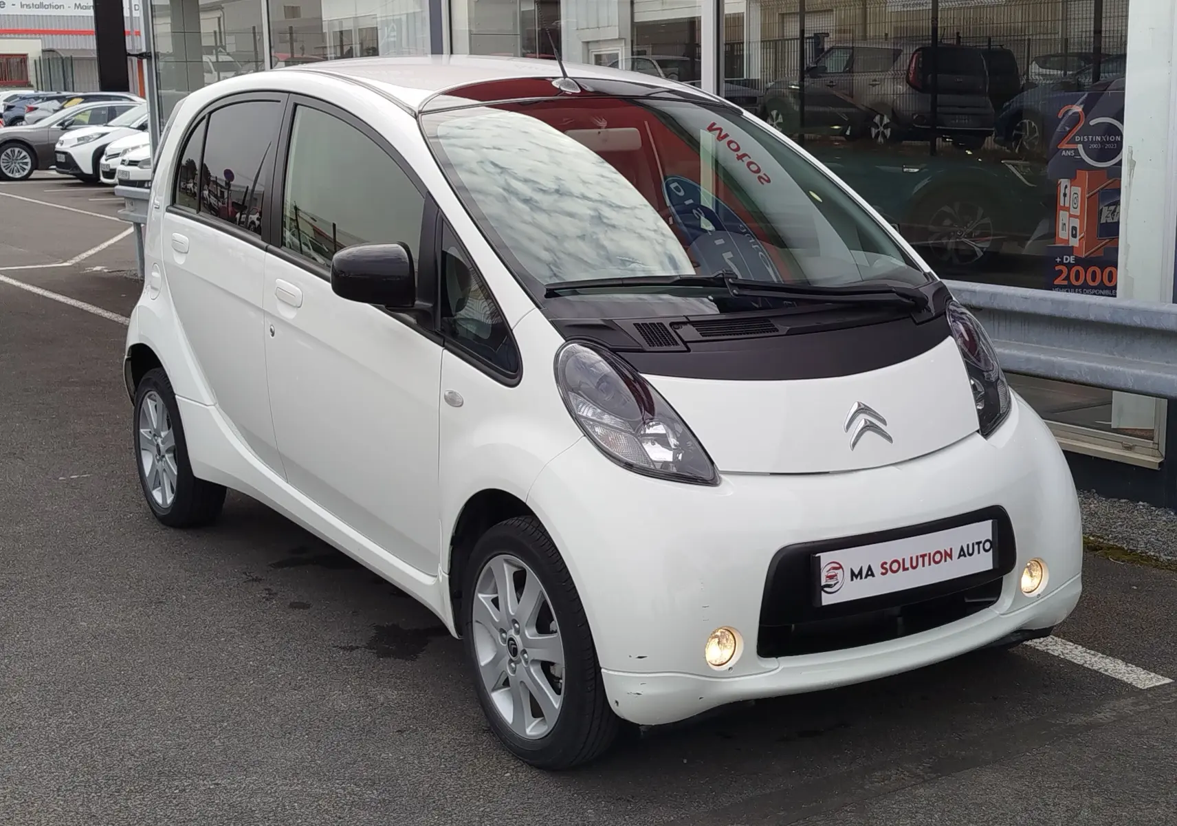 Citroën C-Zero blanc Antarctique vue 3/4 avant droit, avec phares antibrouillard allumés et rétroviseurs noirs.