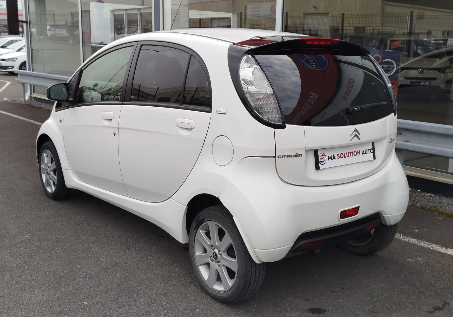 Vue 3/4 arrière droite d'une Citroën C-ZERO Confort blanche Antarctique avec vitres teintées et jantes alliage.