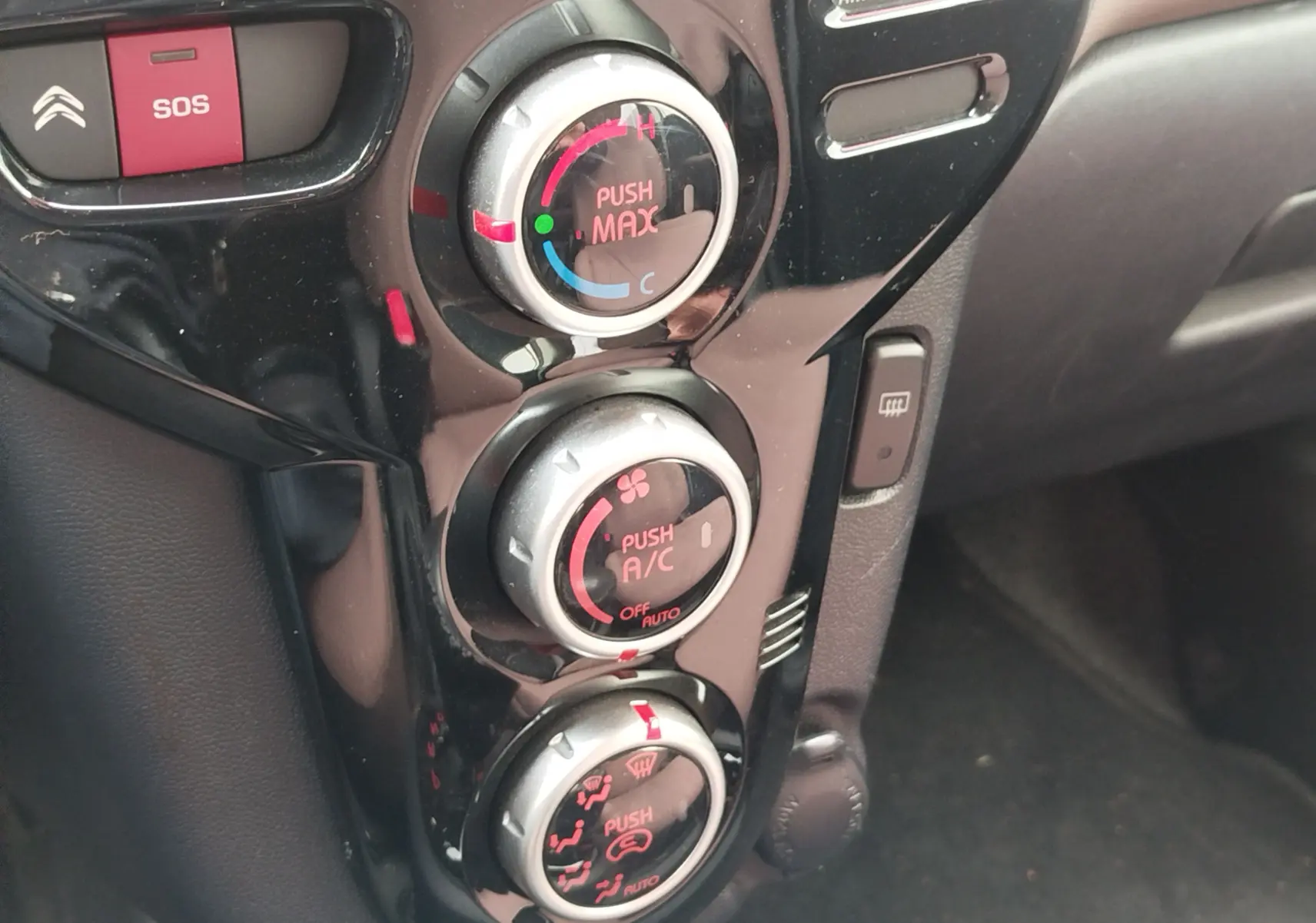 Gros plan sur les commandes de climatisation noires et argentées du tableau de bord d'une Citroën C-ZERO blanc Antarctique.
