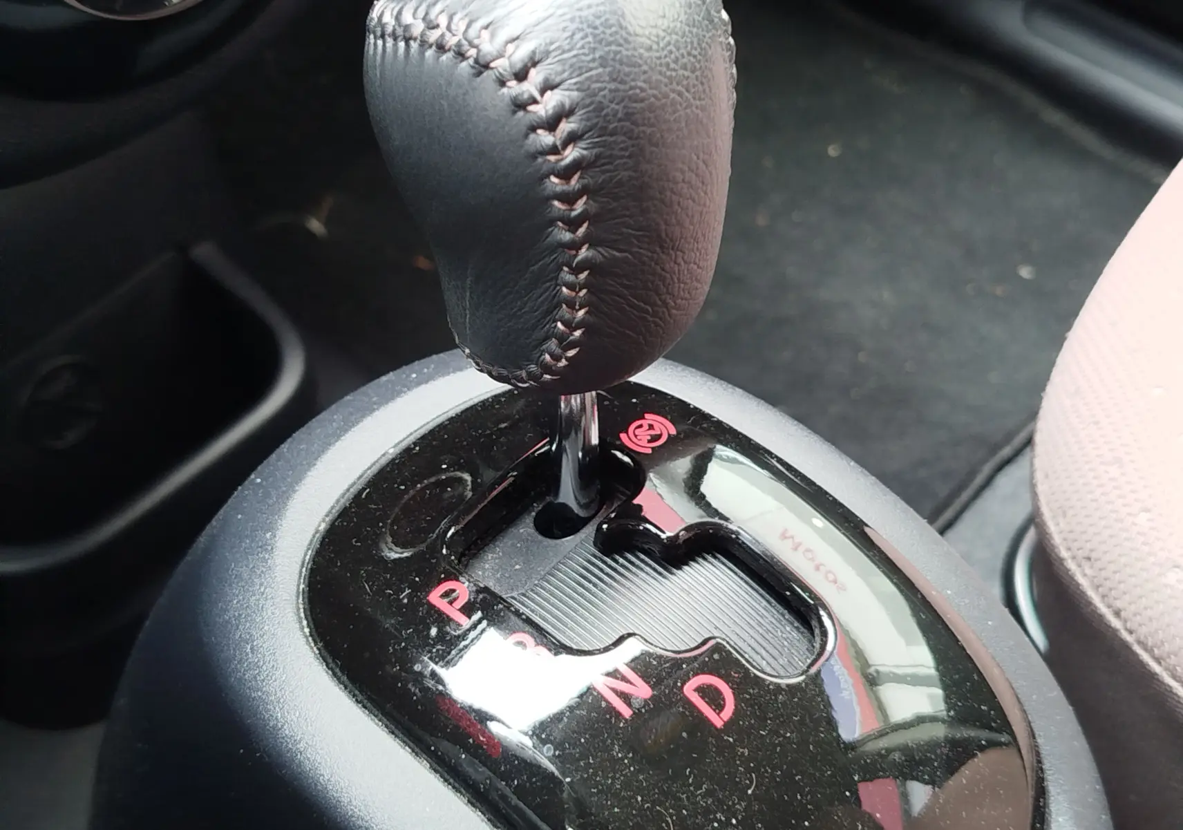 Gros plan sur le levier de vitesses automatique noir avec coutures visibles dans une Citroën C-ZERO blanche, version Confort.