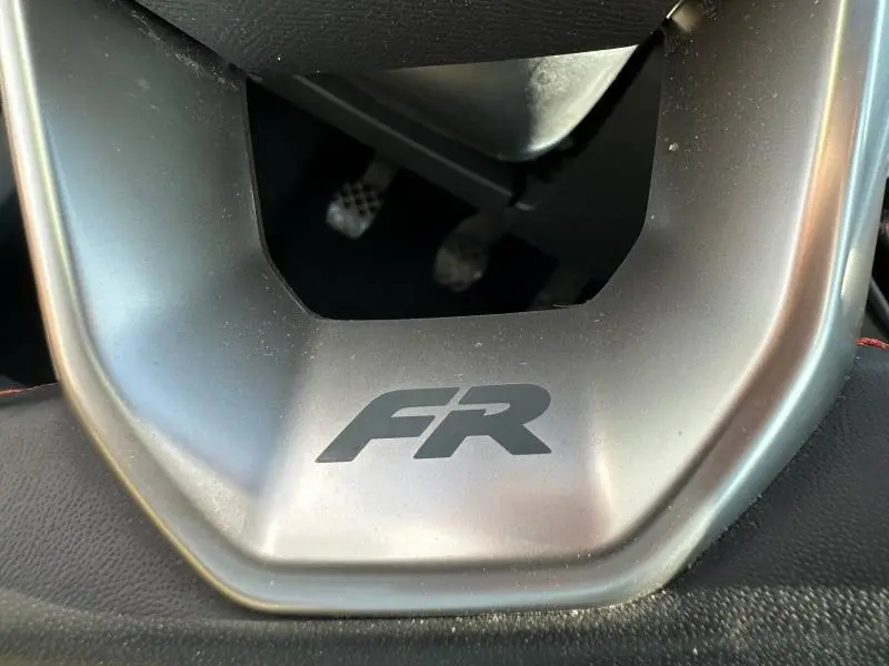 Gros plan sur le volant avec logo FR du SEAT Arona 2025, version 1.0 TSI, intérieur noir avec surpiqûres rouges.