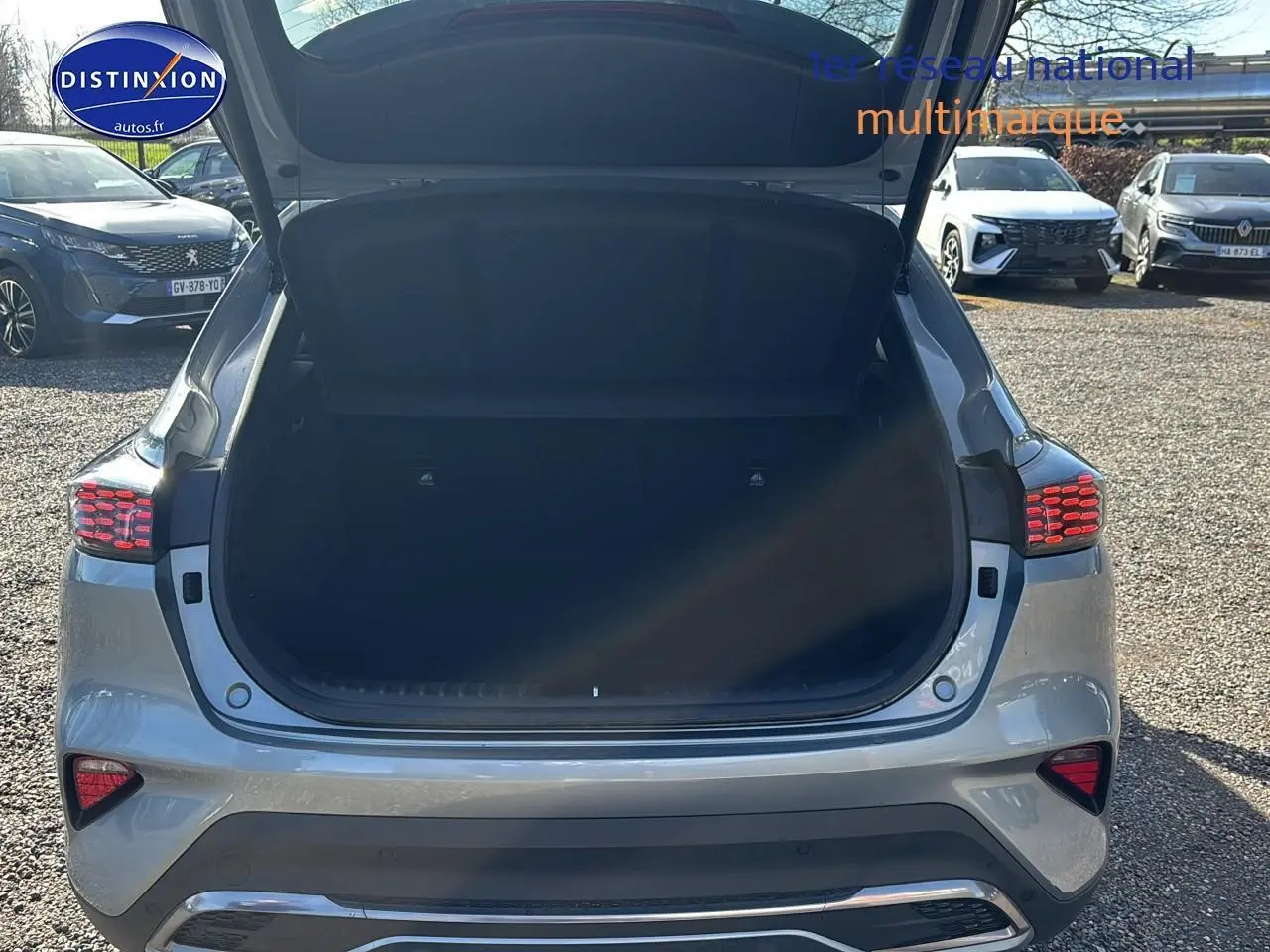 Vue arrière d’un KIA Xceed gris 2024 avec coffre ouvert, feux arrière LED allumés et becquet visible.