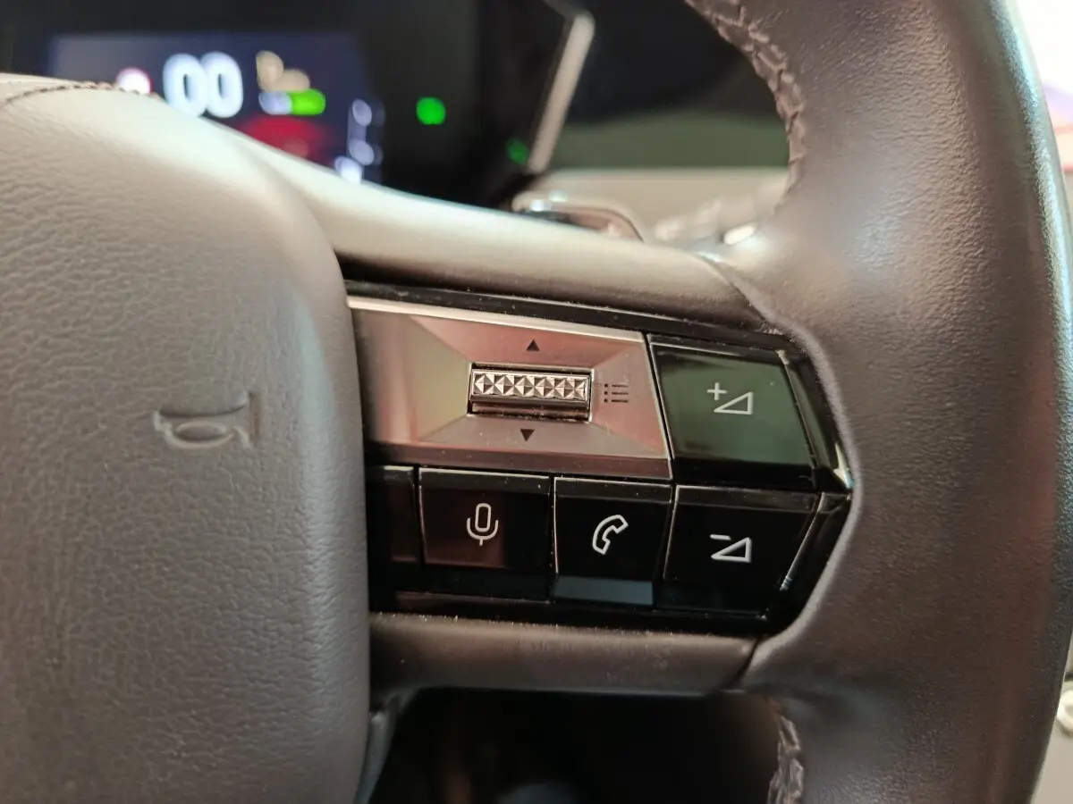 Gros plan sur les commandes à droite du volant cuir noir du DS4 E-TENSE 225 gris clair, avec boutons de volume et appel.