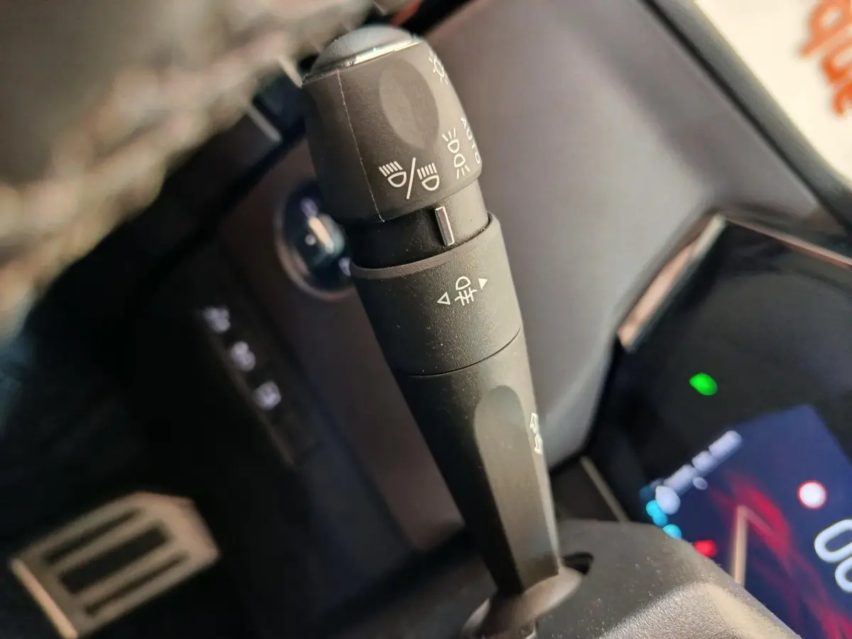 Gros plan sur la commande des feux au volant d’une DS4 E-TENSE 225 gris clair, intérieur noir.
