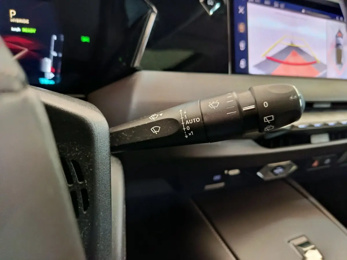 Gros plan sur la manette des essuie-glaces dans l’habitacle d’une DS4 E-TENSE 225 gris clair, avec écran tactile en arrière-plan.