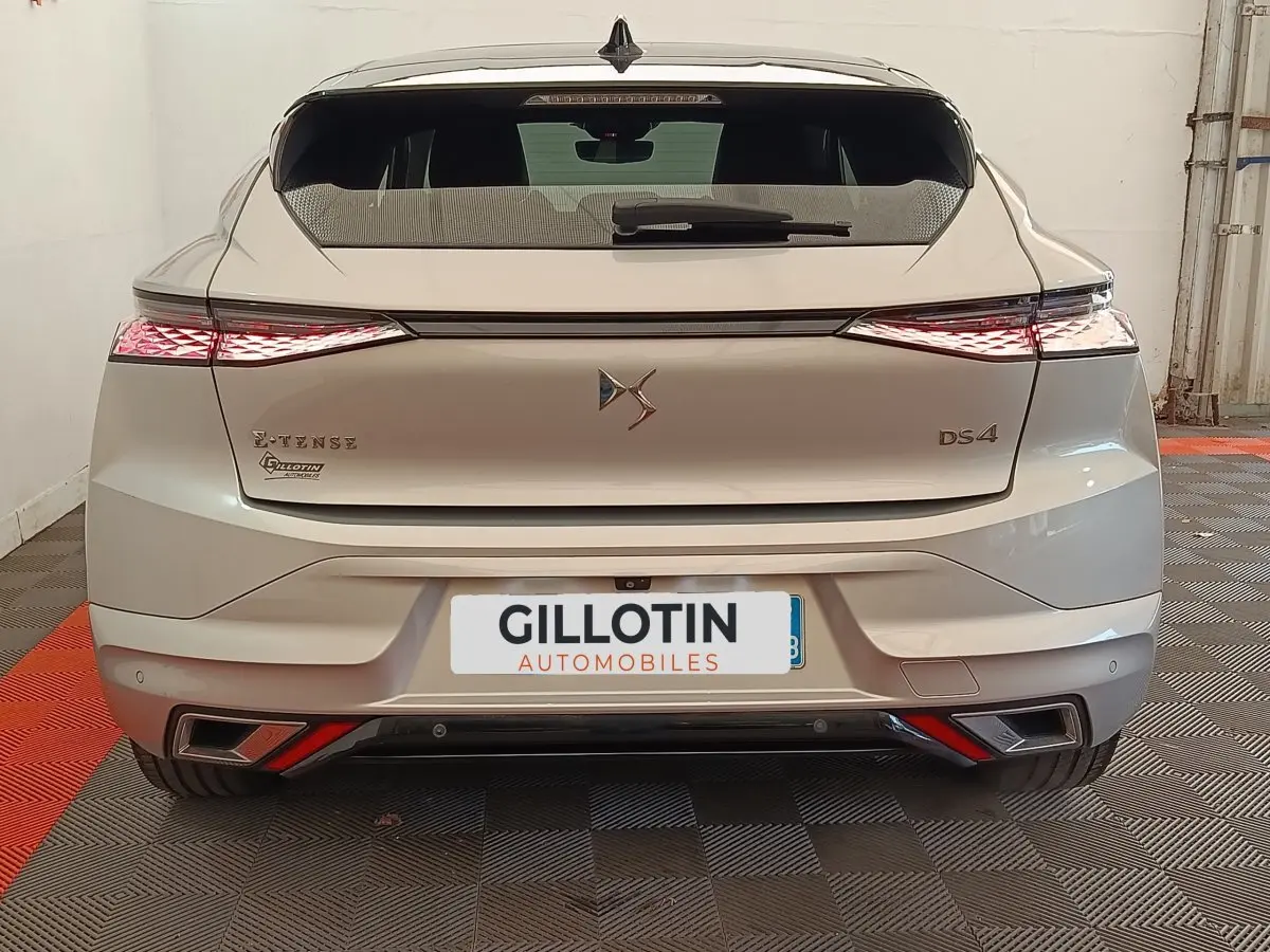 Vue arrière d'une DS4 E-TENSE 225 gris clair avec feux LED étirés et double sortie d'échappement intégrée.
