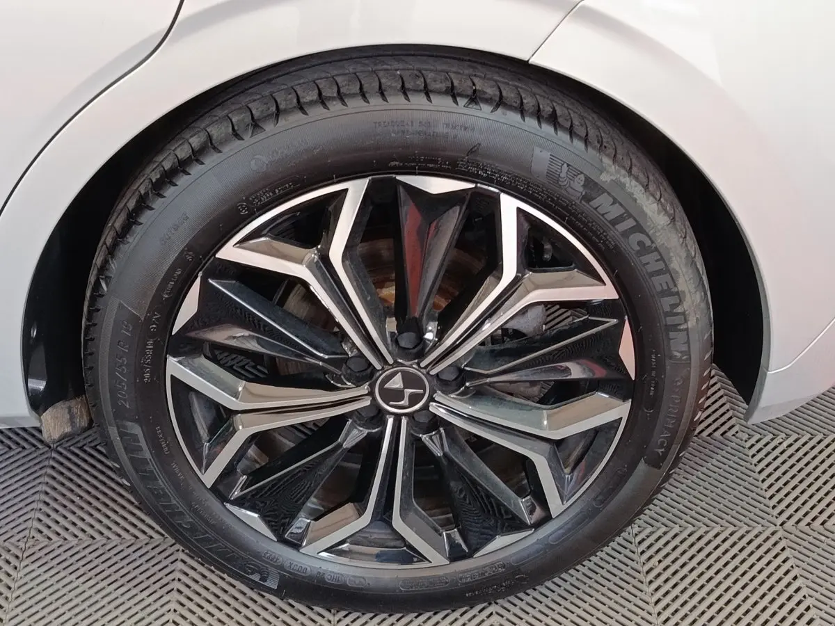 Gros plan sur la roue avant droite d'une DS4 E-TENSE gris clair avec jante noire et argentée au design géométrique.