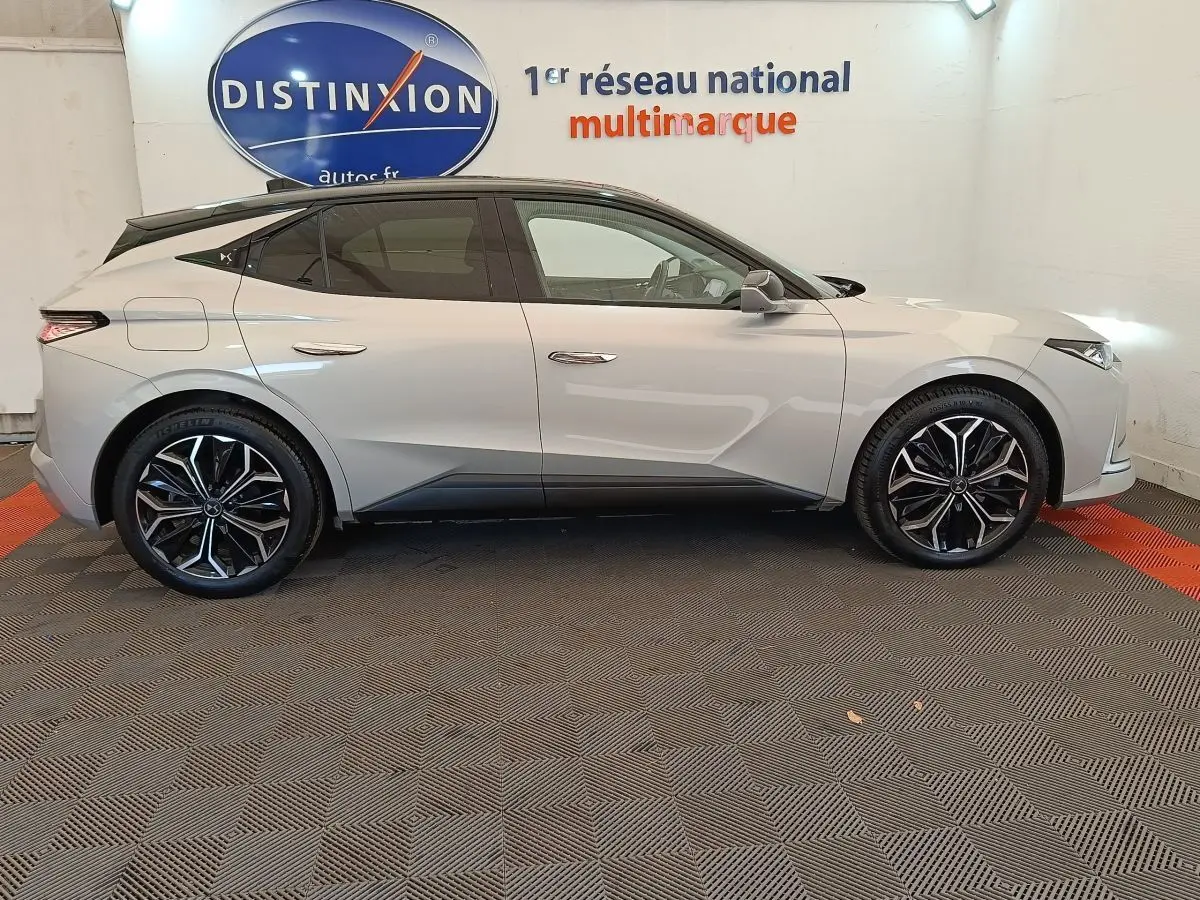 Vue de profil côté gauche d'une DS4 E-TENSE 225 gris clair avec toit noir et jantes alliage distinctives en concession.
