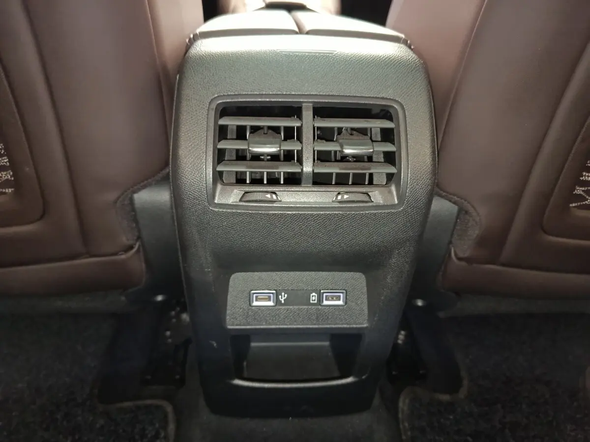 Vue rapprochée de la console arrière noire avec bouches d’aération et ports USB dans l’habitacle du DS4 E-TENSE gris clair.