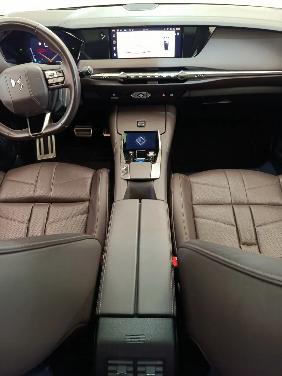 Vue intérieure du poste de conduite du DS4 E-TENSE 225 gris clair, avec tableau de bord numérique et console centrale tactile.