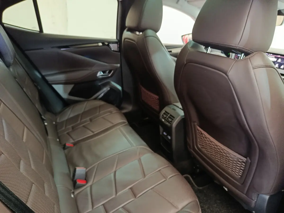 Vue intérieure arrière côté gauche du DS4 E-TENSE 225 gris clair, sièges en cuir marron avec console centrale et aérateurs.