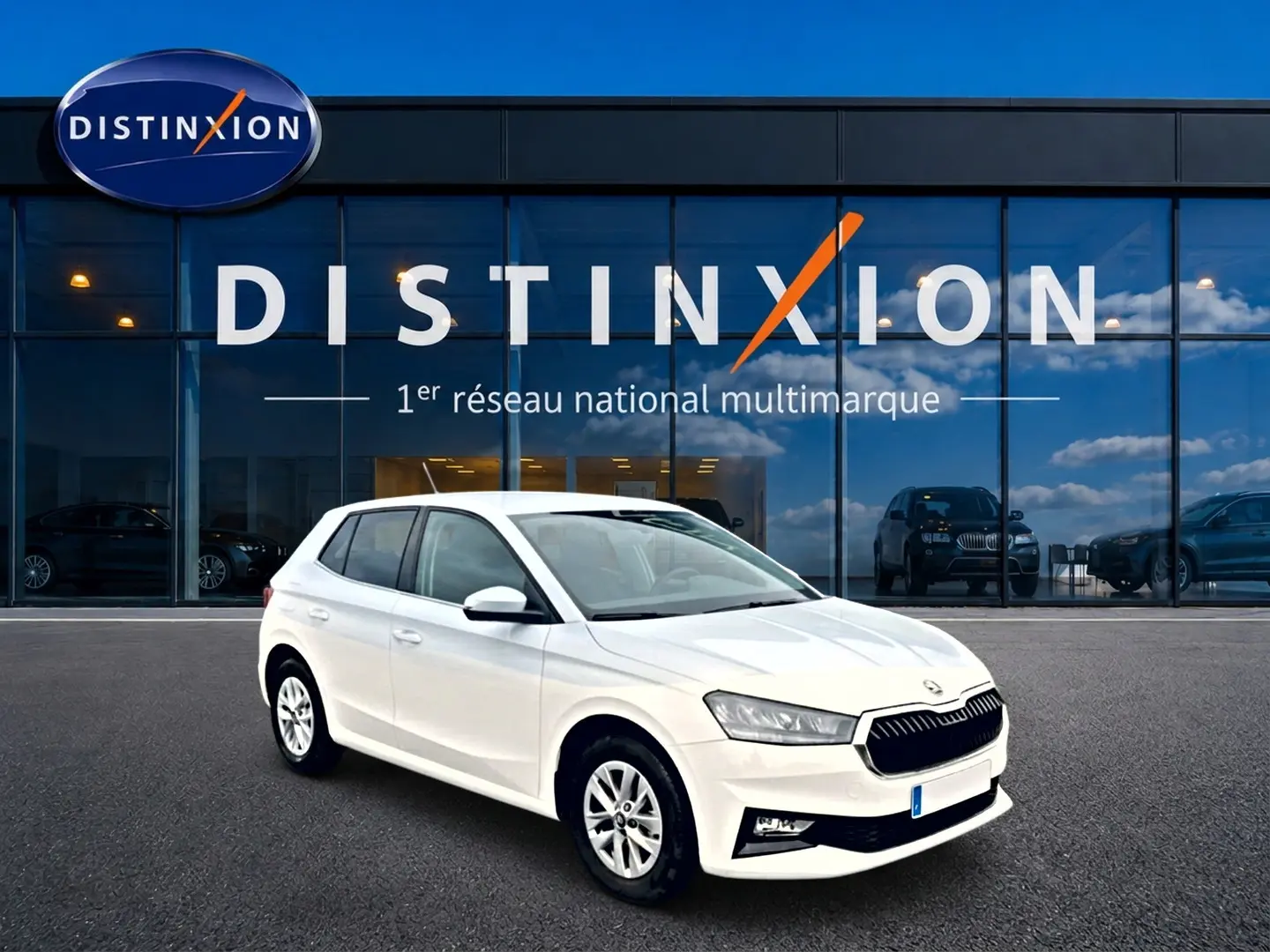 Vue 3/4 avant droite d'une Skoda Fabia blanche stationnée devant une vitrine avec logo Distinxion.
