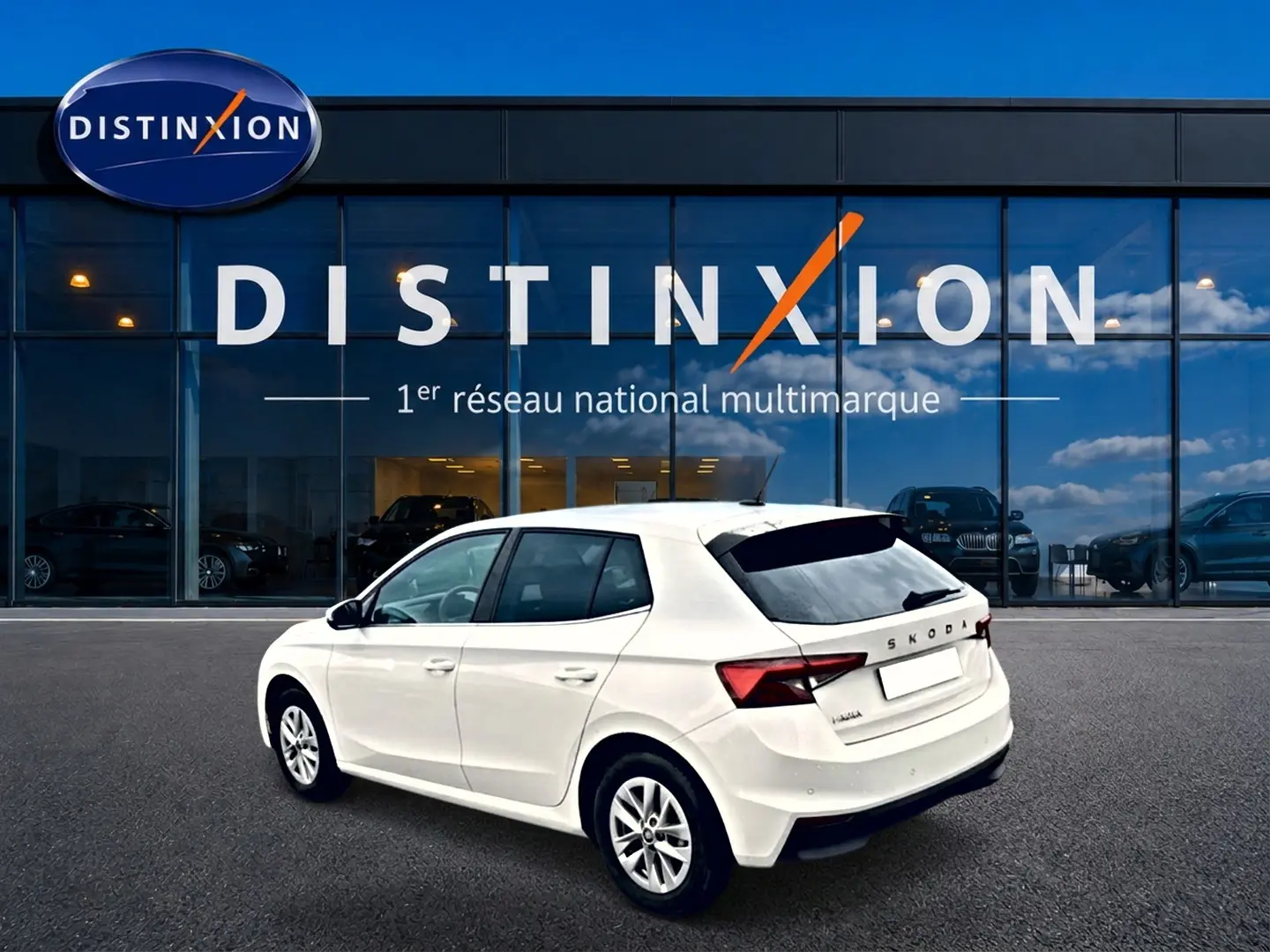Vue 3/4 arrière droite d'une Skoda Fabia blanche 2025 devant une vitrine Distinxion, avec jantes alu et feux LED.