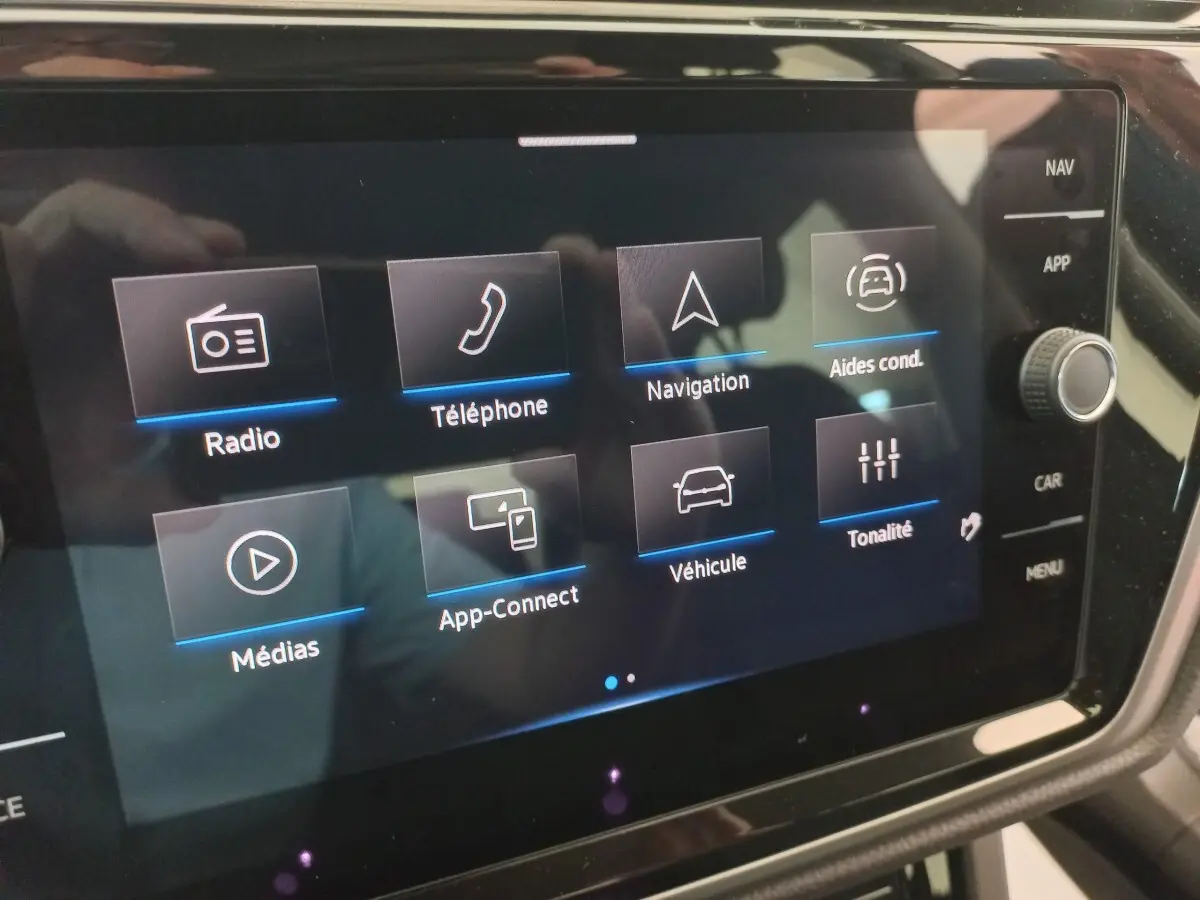 Écran tactile central du Volkswagen Touran 2024 affichant les options radio, téléphone, navigation et aides à la conduite.