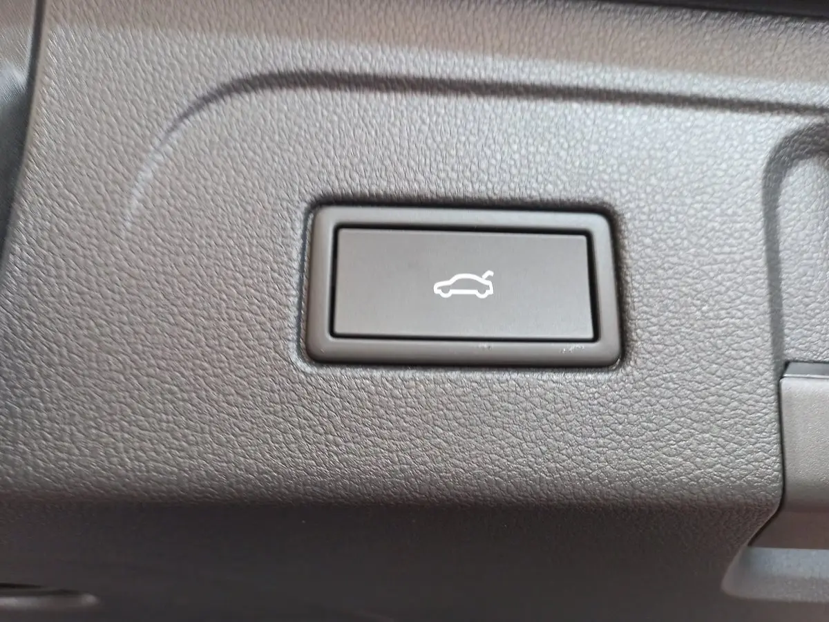 Gros plan sur le bouton d'ouverture électrique du coffre dans l'habitacle noir du Volkswagen Touran 2024.