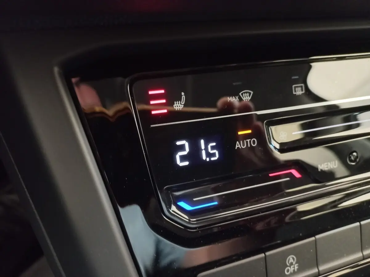 Gros plan sur la commande de climatisation digitale avec affichage de 21,5°C dans un Volkswagen Touran noir 2024.