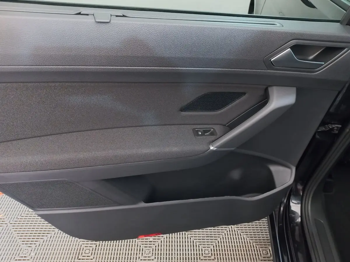 Vue rapprochée de la porte intérieure côté droit noire du Volkswagen Touran 2024 avec poignée argentée et commande de verrouillage.