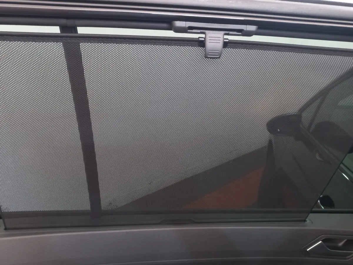 Vue intérieure côté droit du pare-soleil en filet du Volkswagen Touran noir 2024, volet déployé sur la vitre arrière.