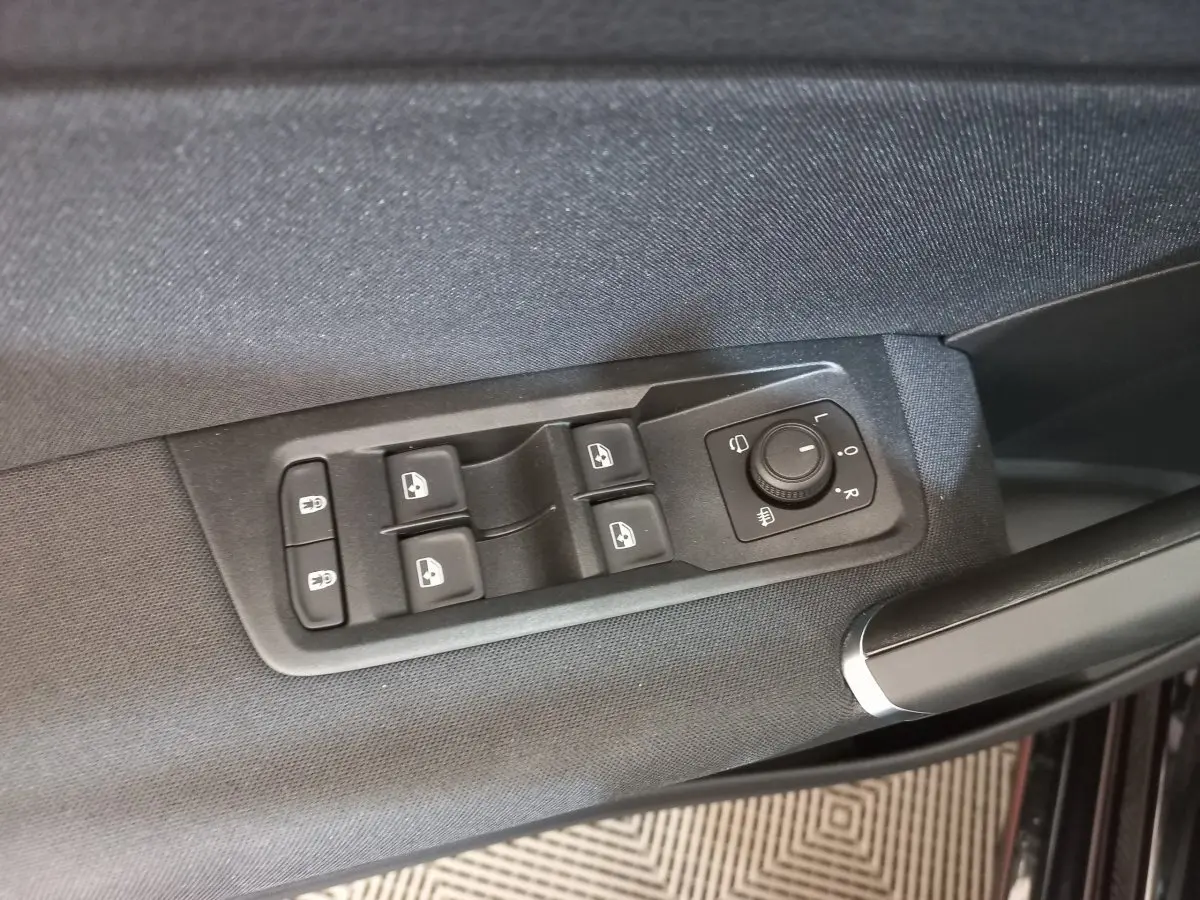 Détail des commandes de lève-vitres et rétroviseurs sur la porte côté conducteur d’un Volkswagen Touran noir 2024.