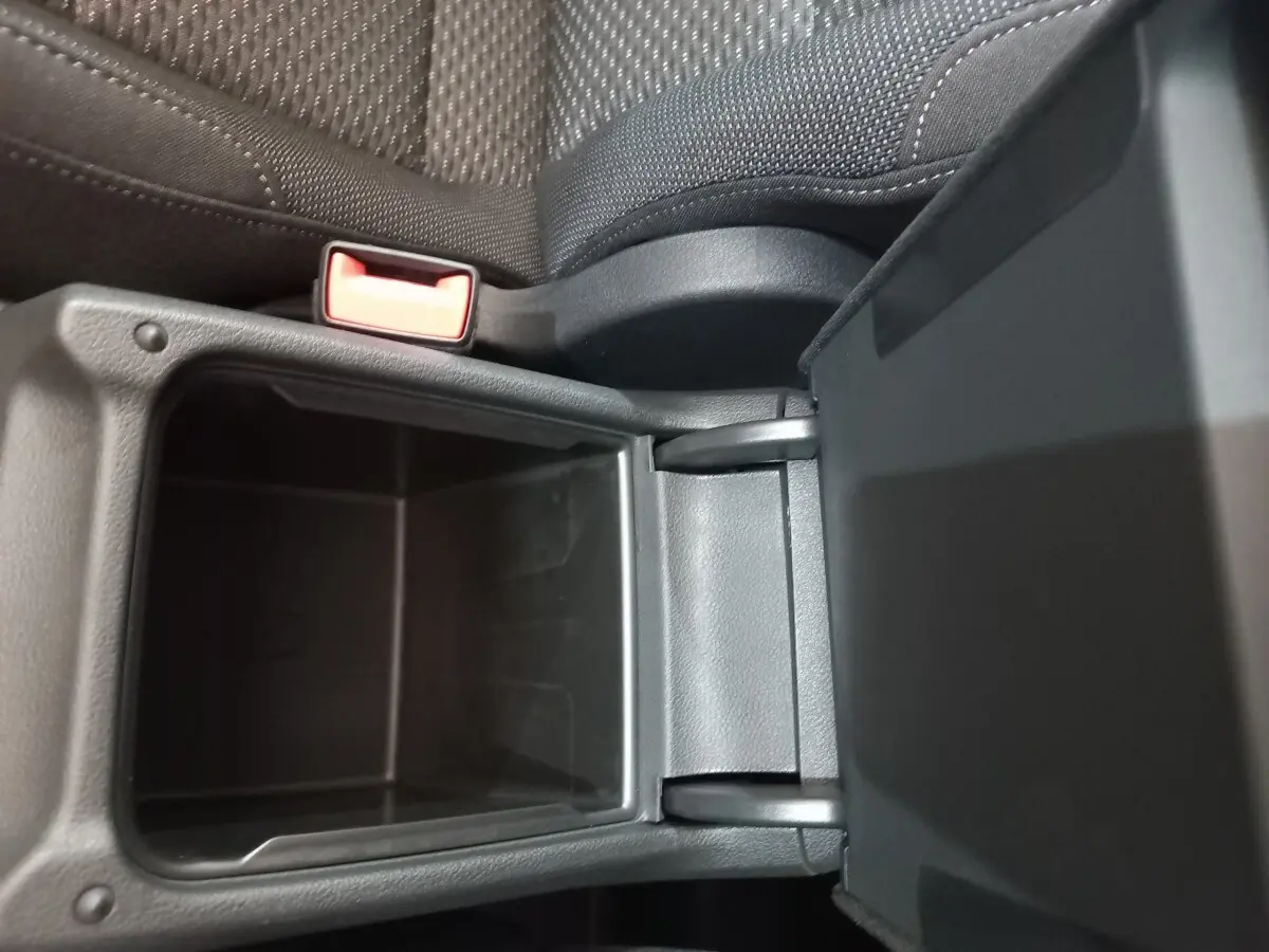 Vue rapprochée du rangement central ouvert, intérieur noir avec tissu et plastique, Volkswagen Touran 2024.