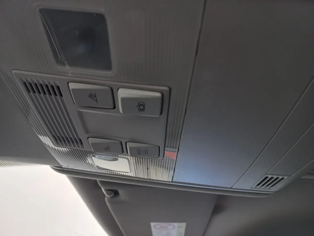 Vue intérieure en gros plan du plafonnier gris avec commandes d’éclairage et verrouillage du Volkswagen Touran 2024 noir.