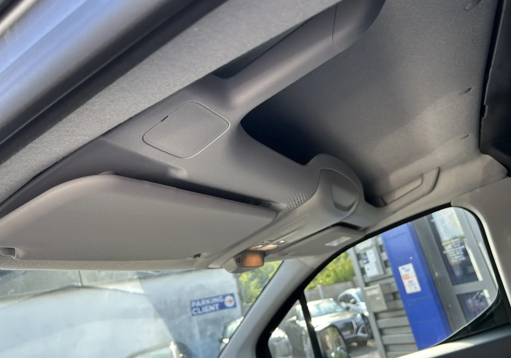 Détail du pare-soleil côté conducteur et plafonnier gris clair à l'intérieur du Peugeot Partner Dangel 4x4 gris Artense.