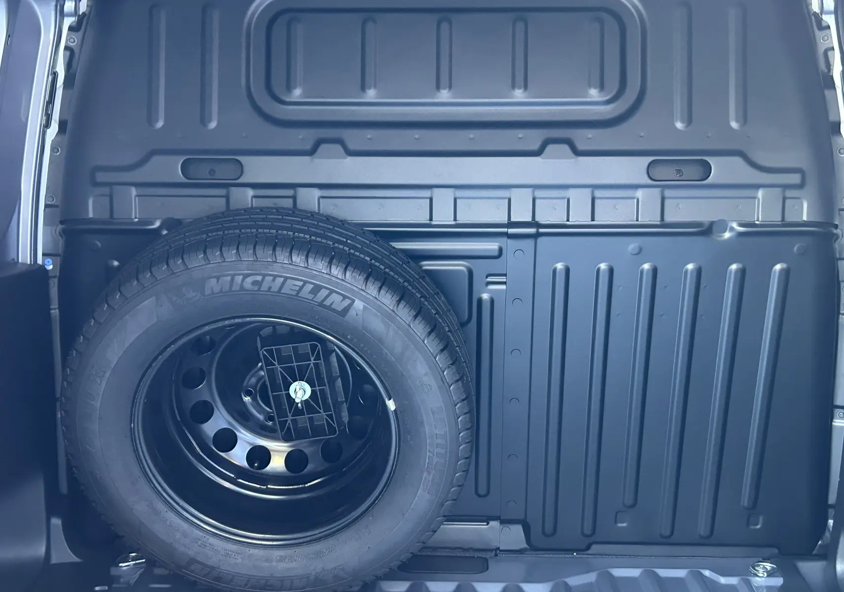 Gros plan sur la roue de secours Michelin montée à l'arrière d'un Peugeot Partner Dangel gris Artense 2025.