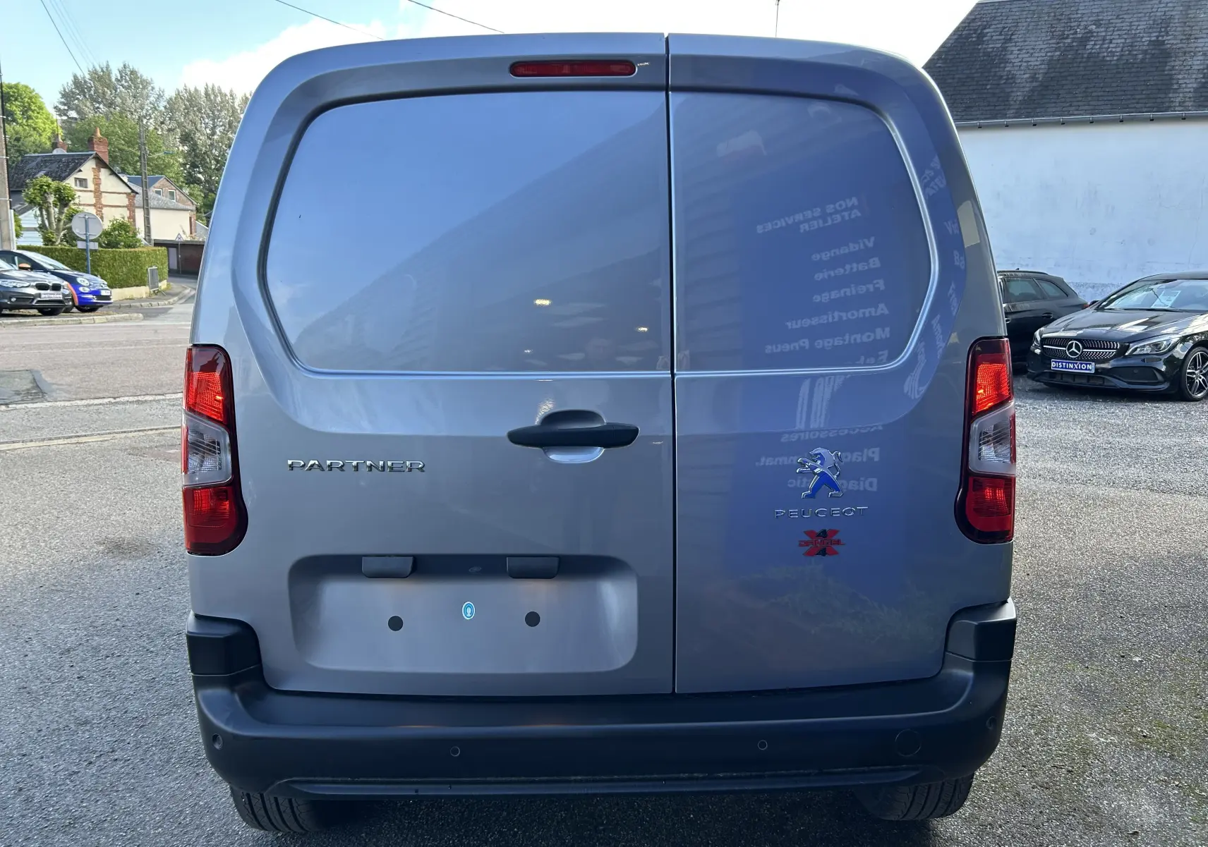 Vue arrière d'un Peugeot Partner gris Artense avec logo Dangel 4x4 et portes battantes fermées.
