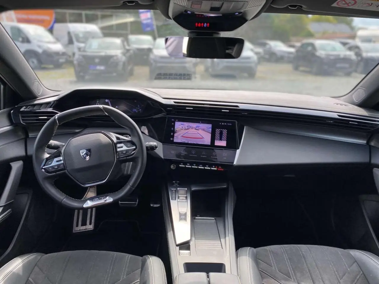 Intérieur Peugeot 308 GT 2023 vu de face, tableau de bord avec écran tactile affichant la caméra de recul.