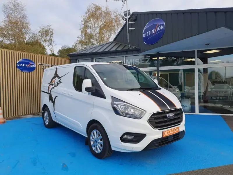 Ford Transit Custom blanc glacier en 3/4 avant droit avec bandes noires sur le capot et marquage poisson sur la porte.