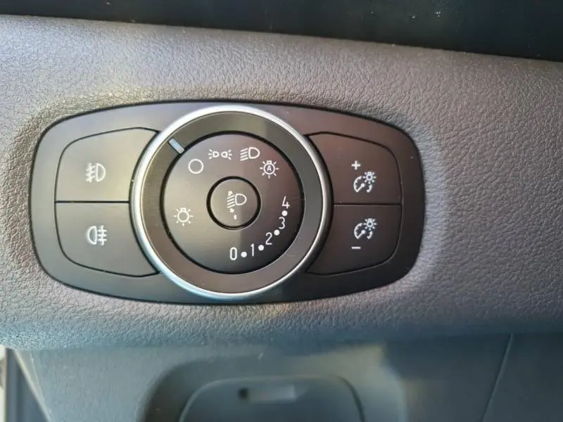 Gros plan sur les commandes d'éclairage du Ford Transit Custom blanc, montrant les réglages de phares et feux antibrouillard.