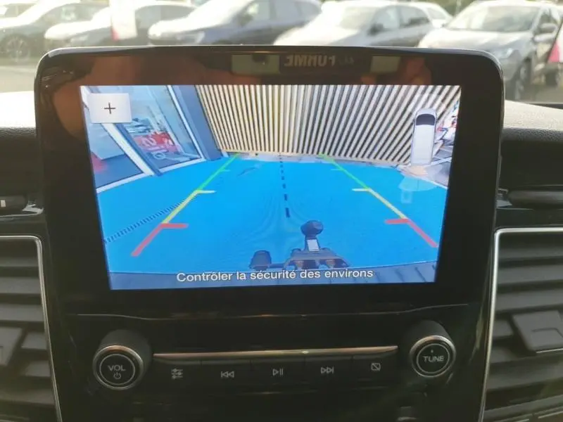 Écran de caméra de recul du Ford Transit Custom blanc montrant la zone arrière avec lignes de guidage colorées et crochet d'attelage visible