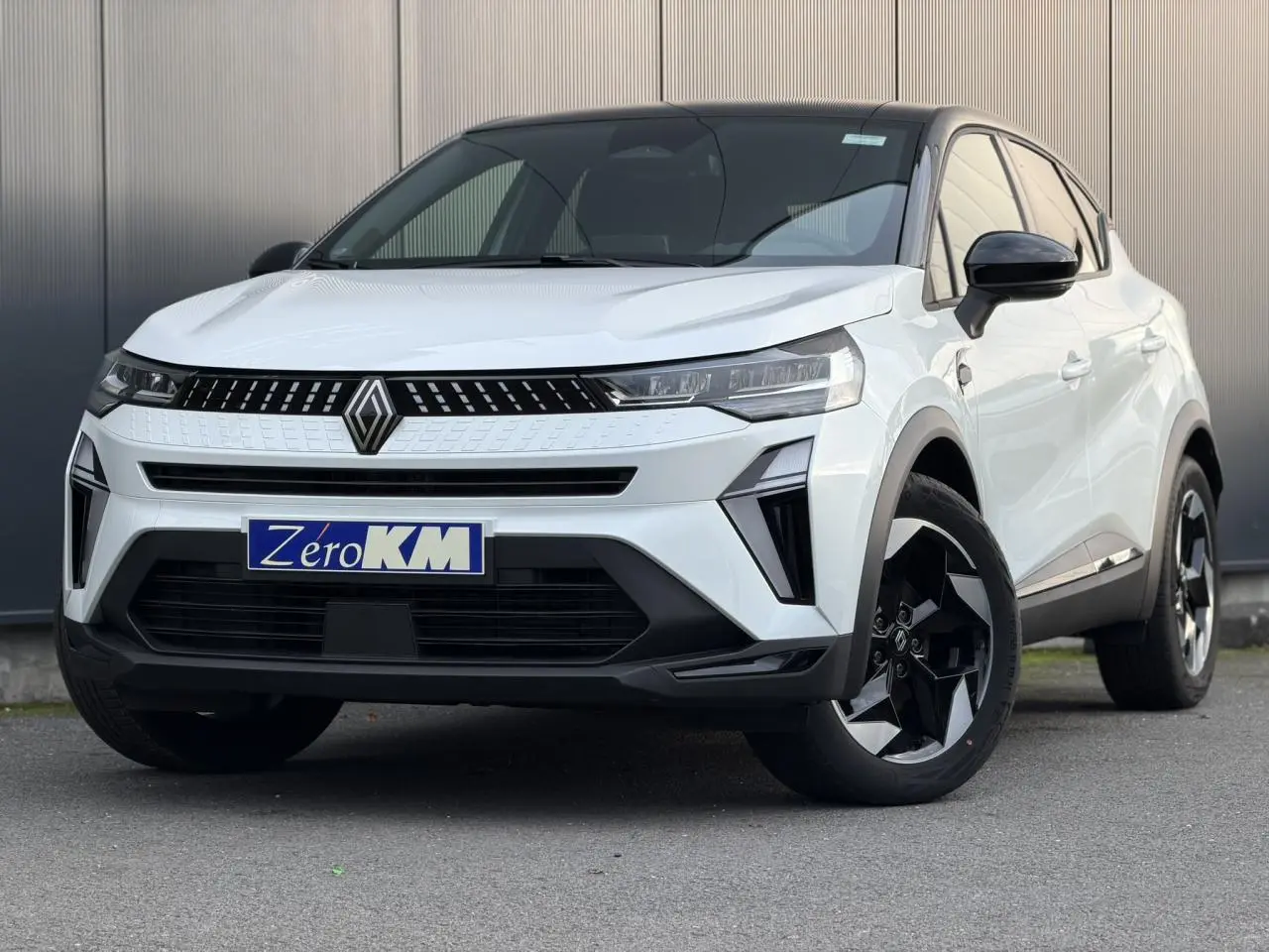 Renault Captur 2025 blanc nacré et noir étoile, vue 3/4 avant avec jantes noires et toit contrasté.
