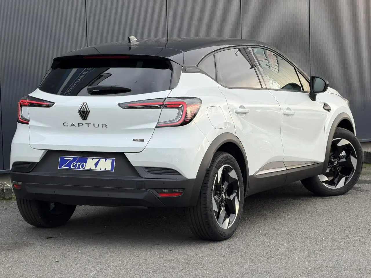 Vue 3/4 arrière droite du Renault Captur blanc nacré et noir étoile avec jantes aluminium 18 pouces et toit noir.